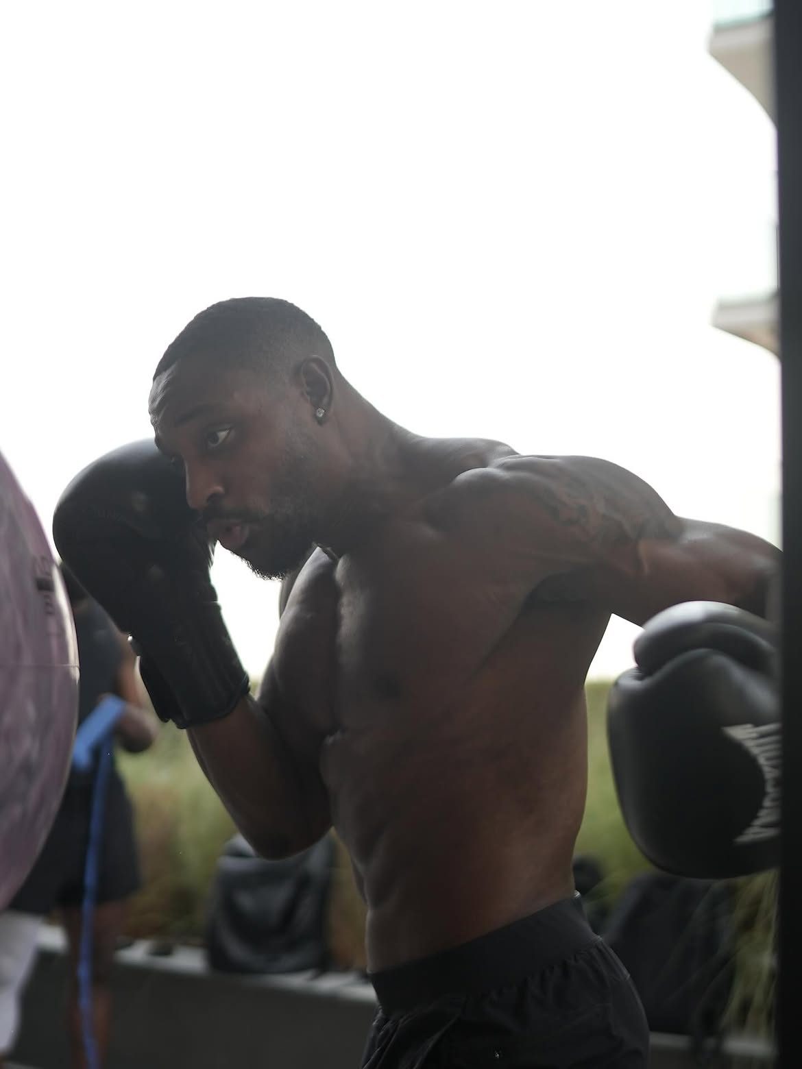 Martel mid-punch in boxing gloves, training outdoors