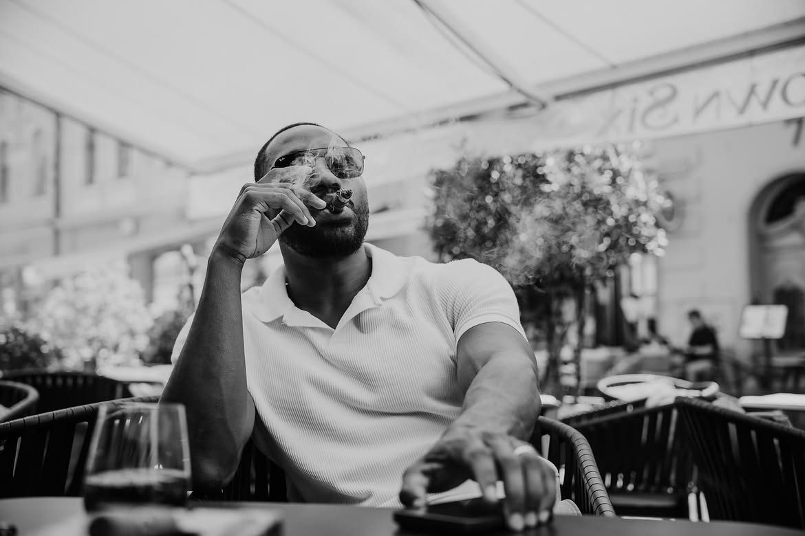 Black and white photo of Martel in sunglasses, looking up on a cafe terrace